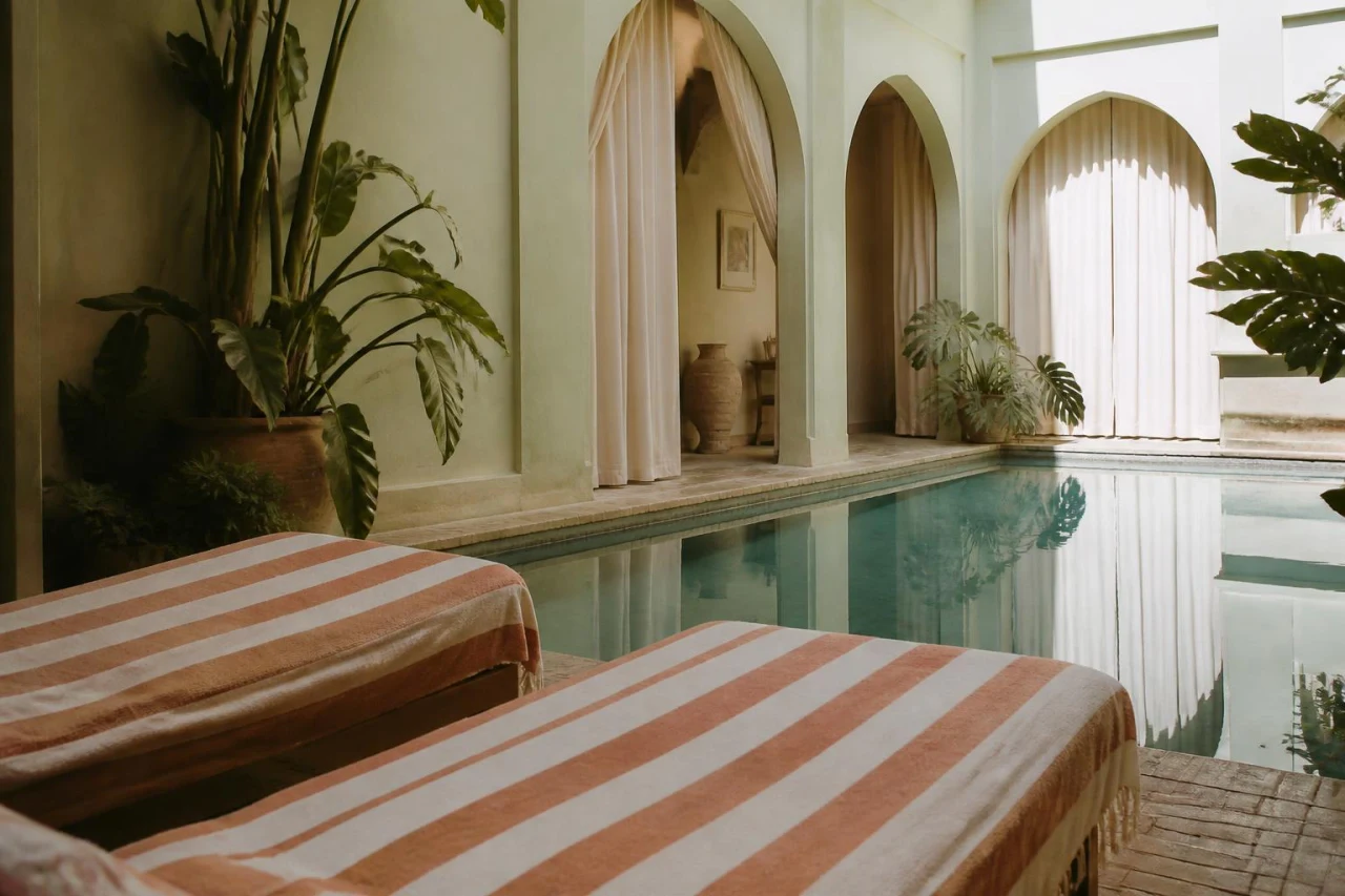 Leerer Hotelpool am Vormittag, daneben Liegen mit gestreiften Handtüchern.